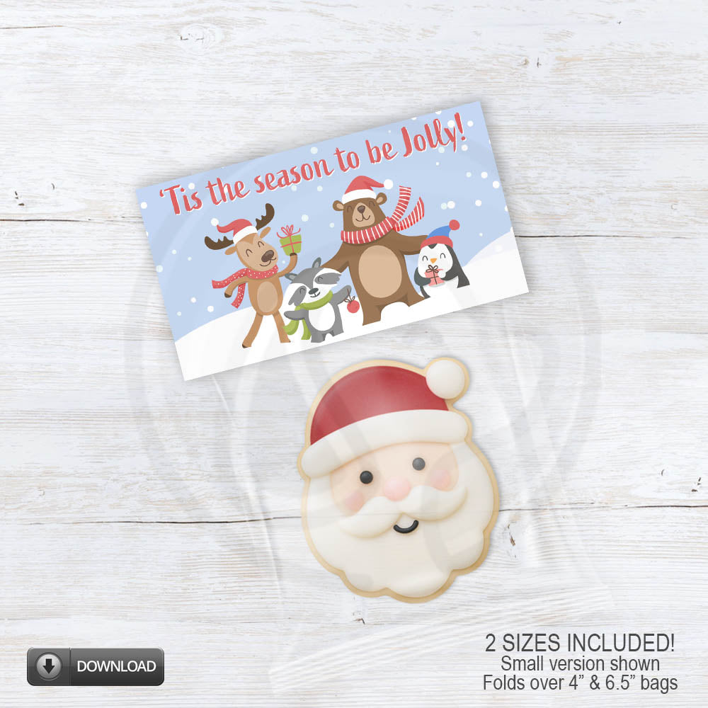 Printable “’Tis the Season to Be Jolly” holiday treat topper featuring reindeer, bear, penguin, and badger in scarves and Santa hats on a snowy blue background — perfect for folding over 4" and 6.5" holiday treat bags.