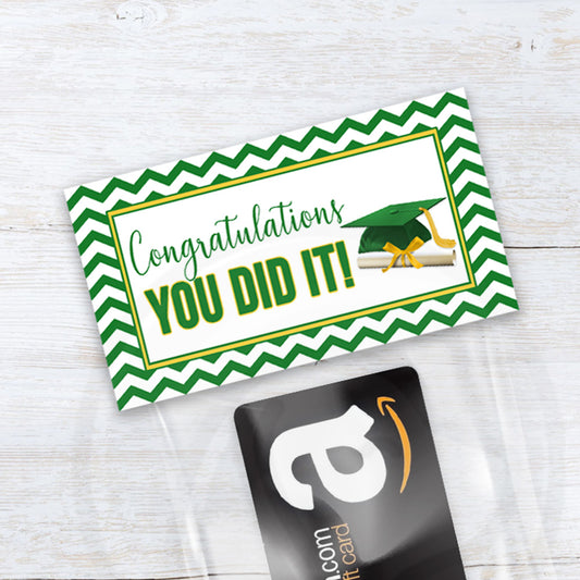 Graduation-themed card with green and white design and a gift card on a wooden surface