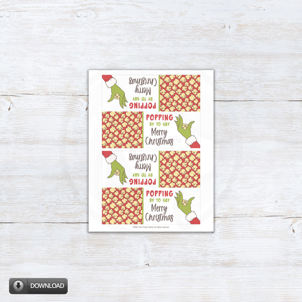 Printable Christmas popcorn bag topper with red background and green cartoon hand. Red holiday treat bag topper saying “Popping by to say Merry Christmas”