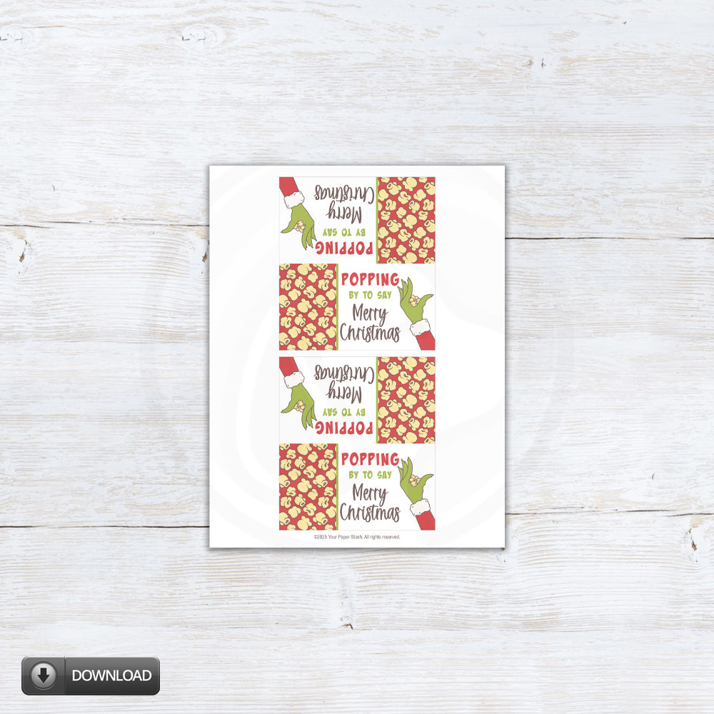 Printable Christmas popcorn bag topper with red background and green cartoon hand. Red holiday treat bag topper saying “Popping by to say Merry Christmas”