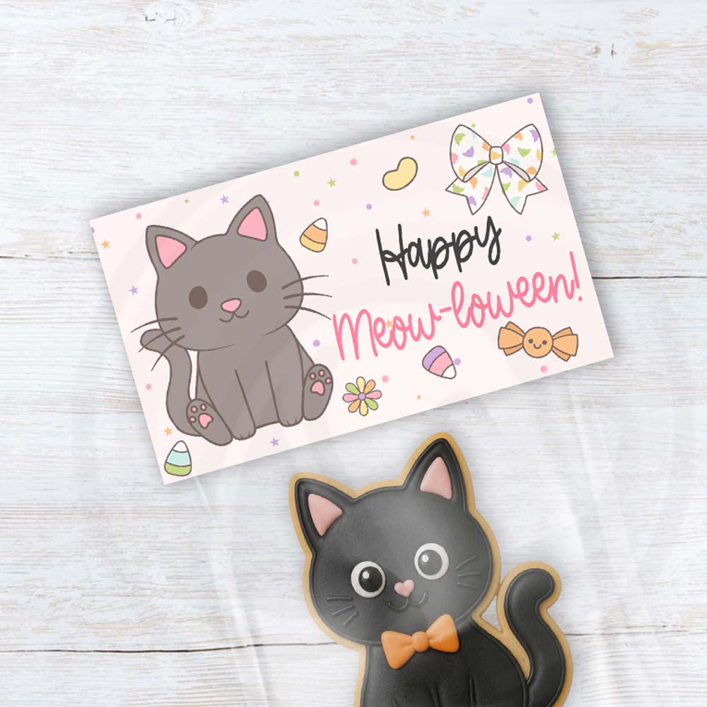 Happy Meow-loween printable Halloween treat bag topper with a cute charcoal gray cat, floral bow, colorful candy, flowers, and pastel stars.