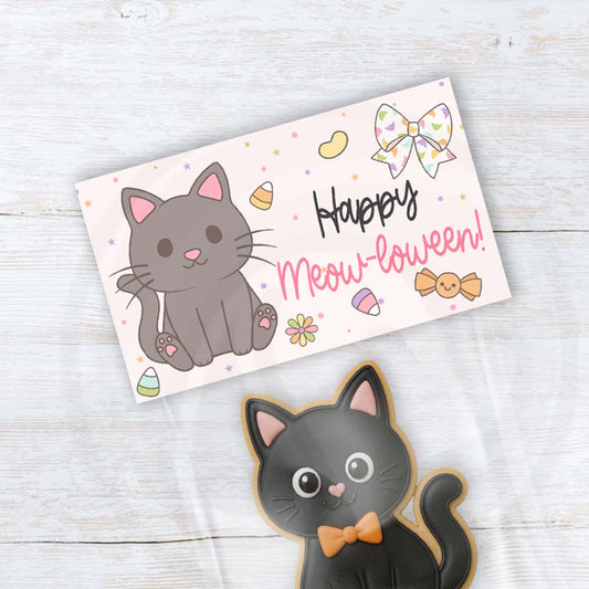 Happy Meow-loween printable Halloween treat bag topper with a cute charcoal gray cat, floral bow, colorful candy, flowers, and pastel stars.