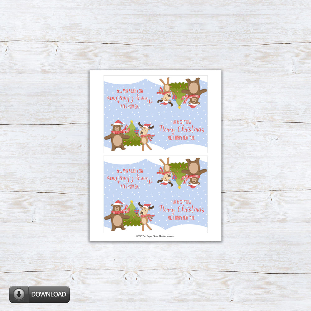 Printable Christmas treat bag topper featuring a cute reindeer and bear in scarves dancing by a Christmas tree with “We wish you a Merry Christmas and a Happy New Year” text on a snowy blue background.